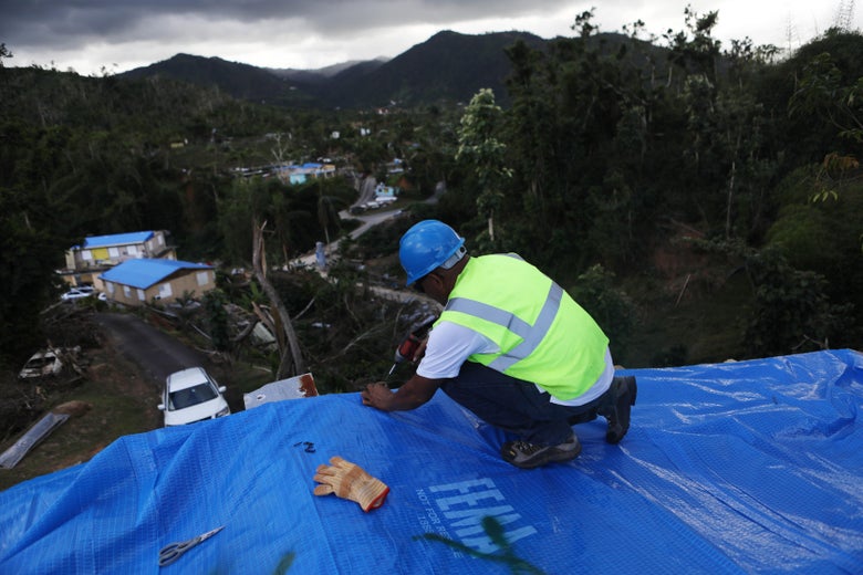 MOROVIS, PUERTO RICO - DECEMBER 20: A contractor helps apply a FEMA tarp to a home damaged by Hurricane Maria on December 20, 2017 in Morovis, Puerto Rico. Barely three months after Hurricane Maria made landfall, approximately one-third of the devastated island is still without electricity and 14 percent lack running water. While the official death toll from the massive storm remains at 64, The New York Times recently reported the actual toll for the storm and its aftermath likely stands at more than 1,000. Puerto Rico's governor has ordered a review and recount as the holiday season approaches. (Photo by Mario Tama/Getty Images)